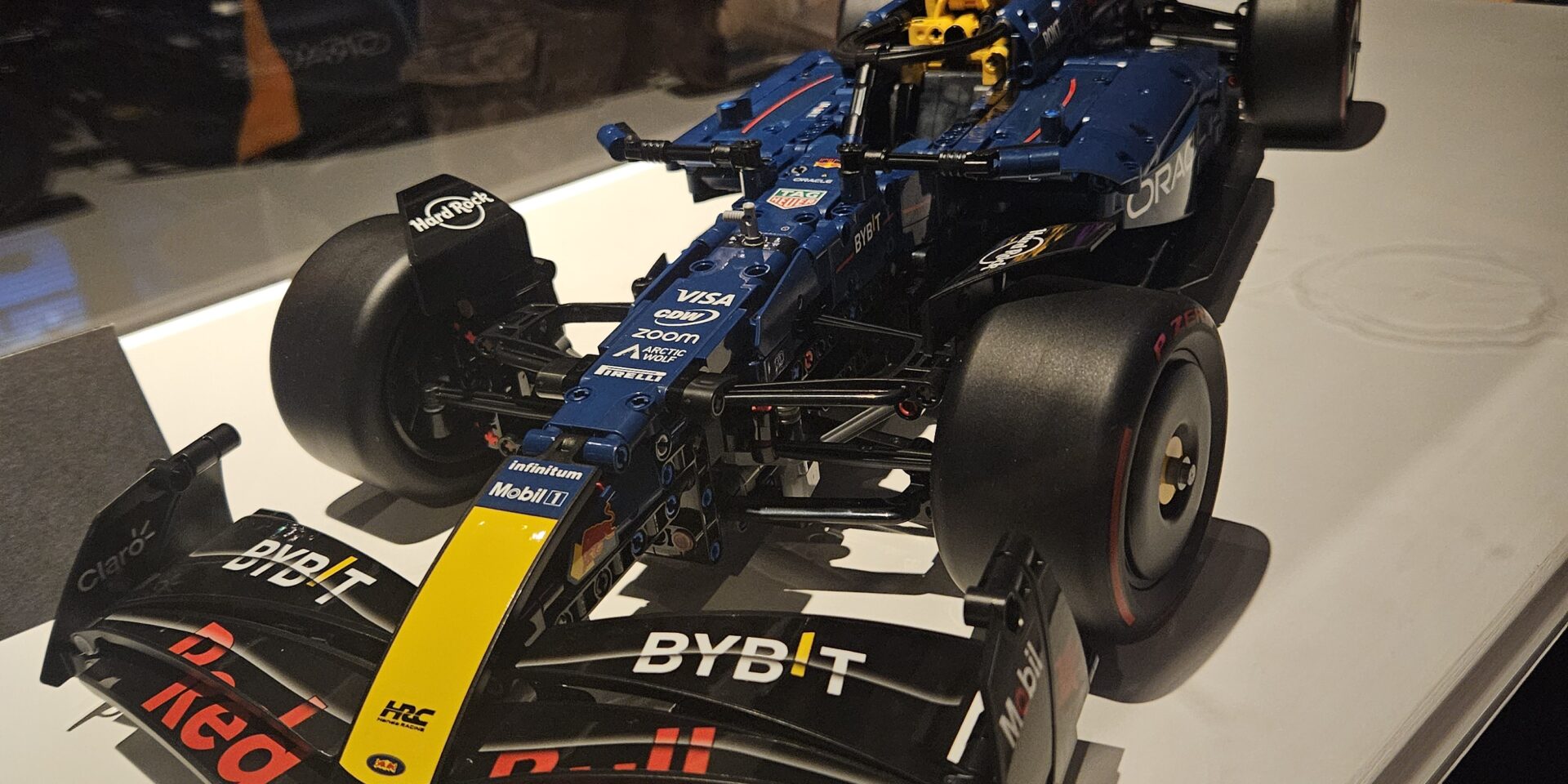 A blue, red and gold Red Bull race car made from Lego is shown in a display case.