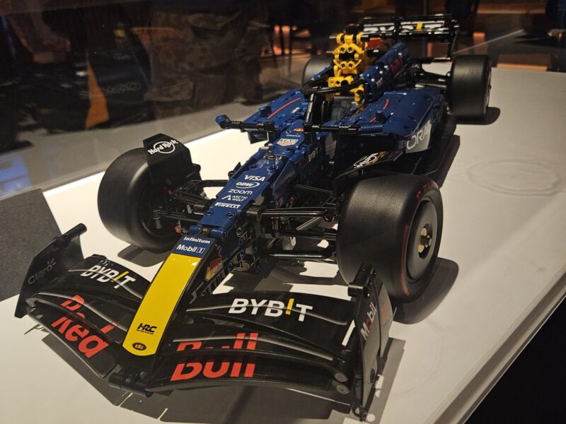 A blue, red and gold Red Bull race car made from Lego is shown in a display case.